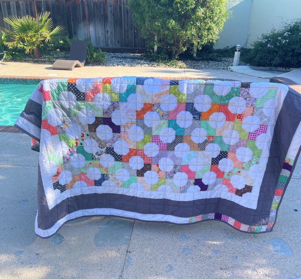 twin size bow tie quilt drying outdoors, hanging over outdoor chairs near pool