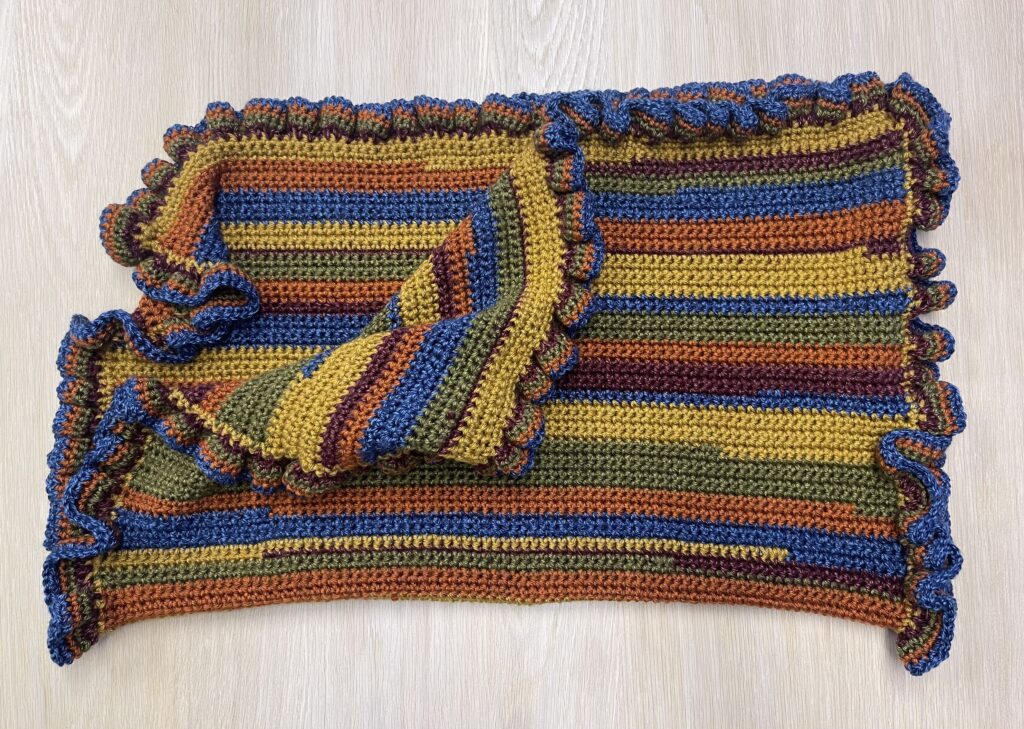 staggered crochet baby blanket folded in half and laid out on hard surface