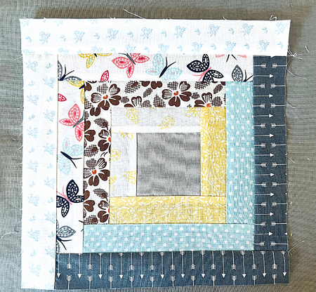 log cabin quilt block laying on ironing board