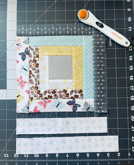 fabric pieces and rotary cutter on cutting mat
