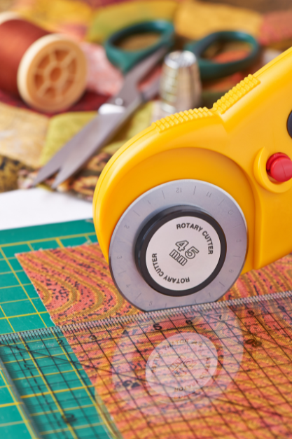 rotary cutter slicing fabric with ruler and cutting matt