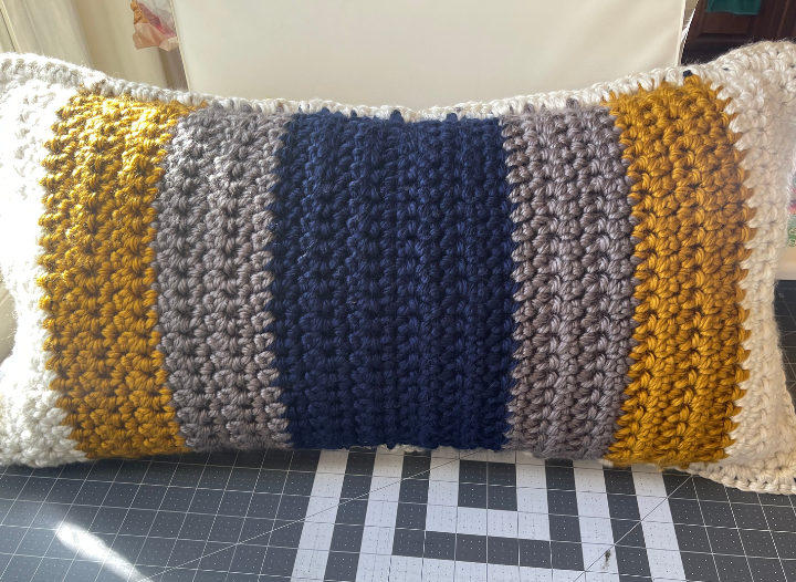 crocheted lumbar pillow laying on cutting matt