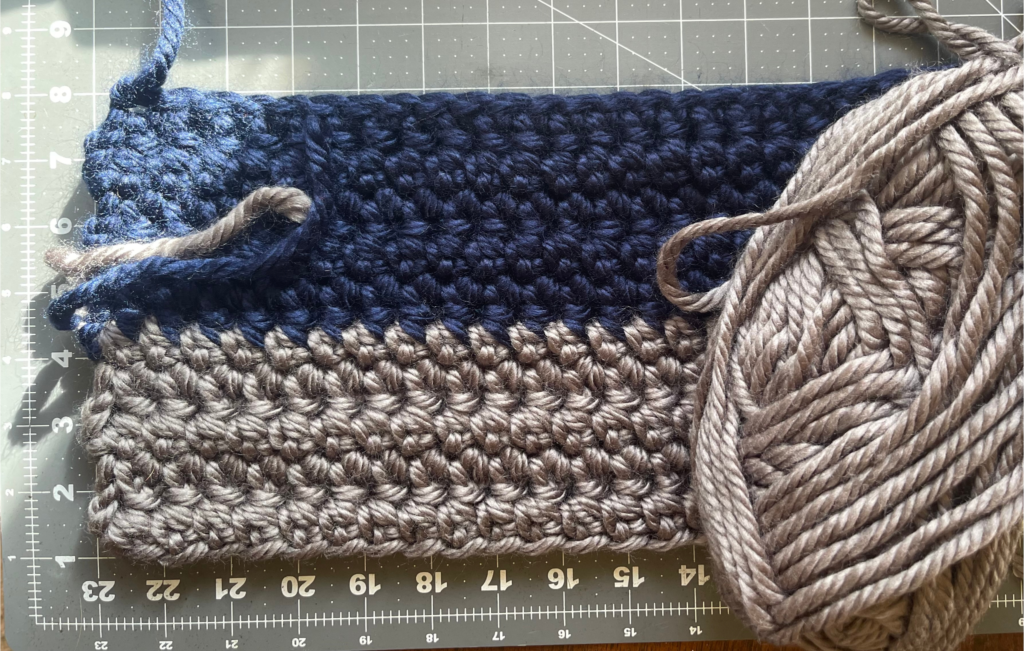 crocheted rows of yarn with skein and crochet hook