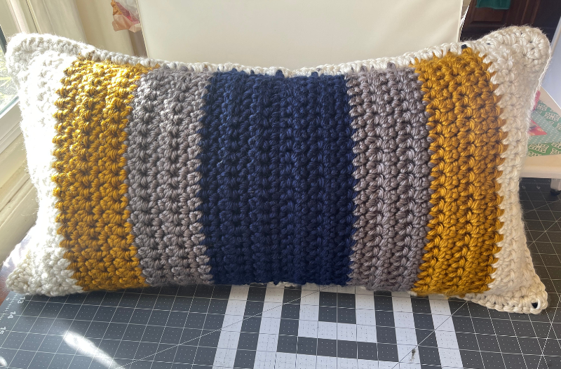 crocheted lumbar pillow laying on cutting matt