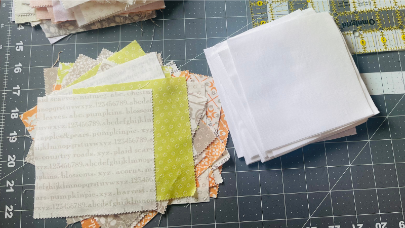 two piles of quilting charm squares on cutting matt