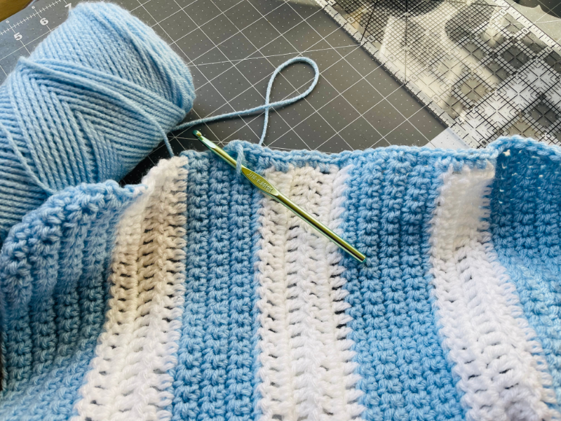 crochet hook and yarn making first row of baby blanket crochet border
