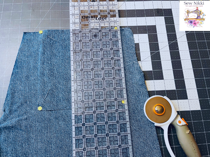 cutting jeans with quilt ruler and rotary cutter on cutting matt