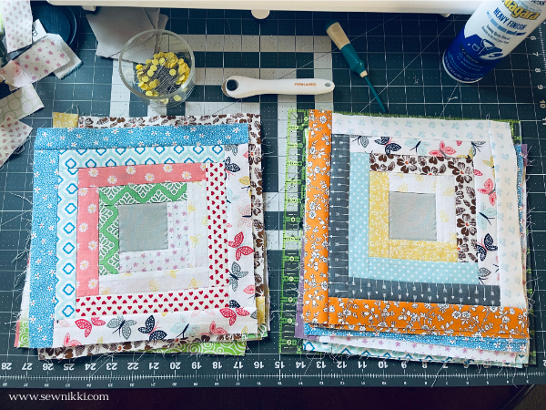 log cabin quilt blocks on cutting mat with sewing supplies
