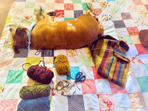 My dog Rose laying on a charm square king size quilt and crochet blanket in progress