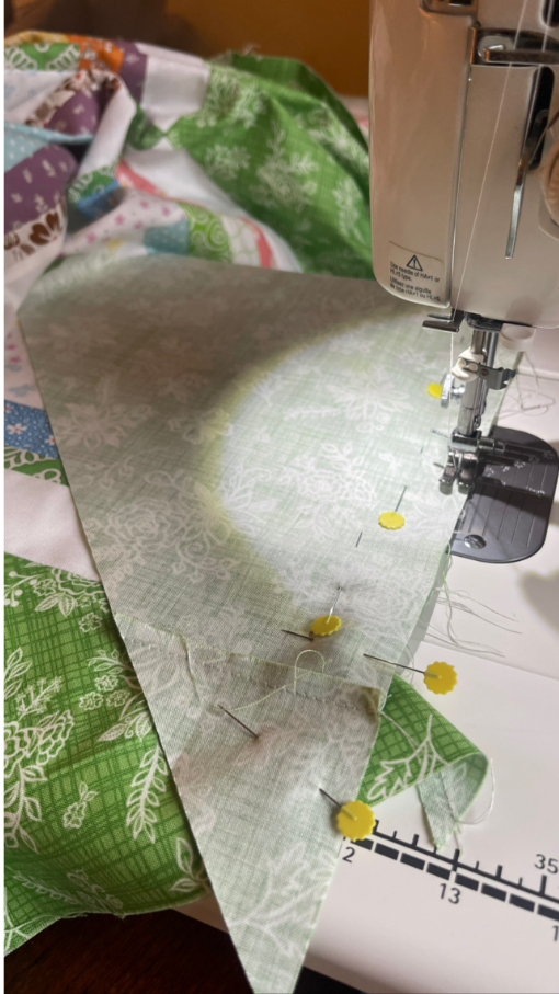 Attaching setting triangles to the end of a quilt row on point quilt by Sew Nikki.