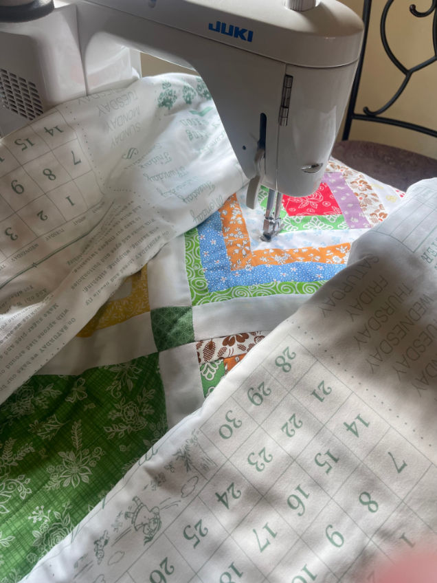 How to quilt on a regular sewing machine - roll up both sides of the quilt to fit it under the throat of machine by Sew Nikki.