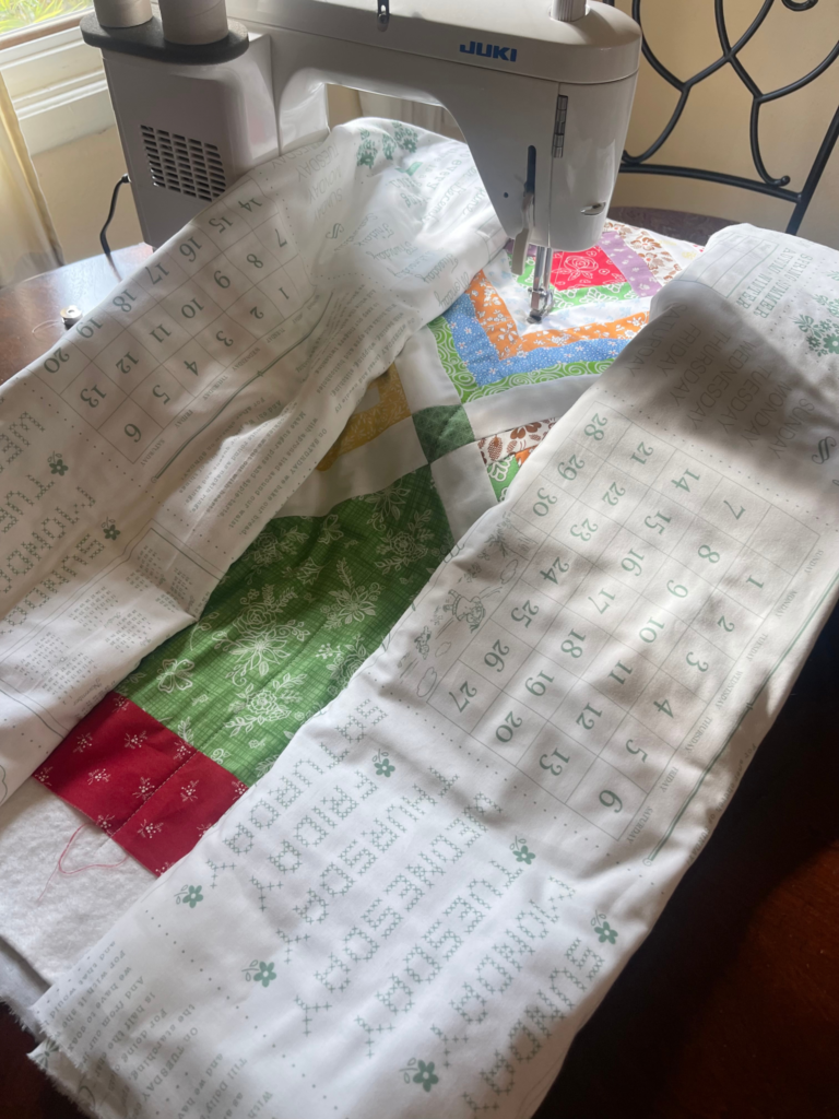 How to quilt on a sewing machine - start in the middle with the quilt rolled up on both sides and begin quilting by Sew Nikki
