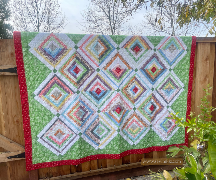 Log Cabin Quilt Pattern On Point by Sew Nikki - Completed twin size quilt hanging over fence.