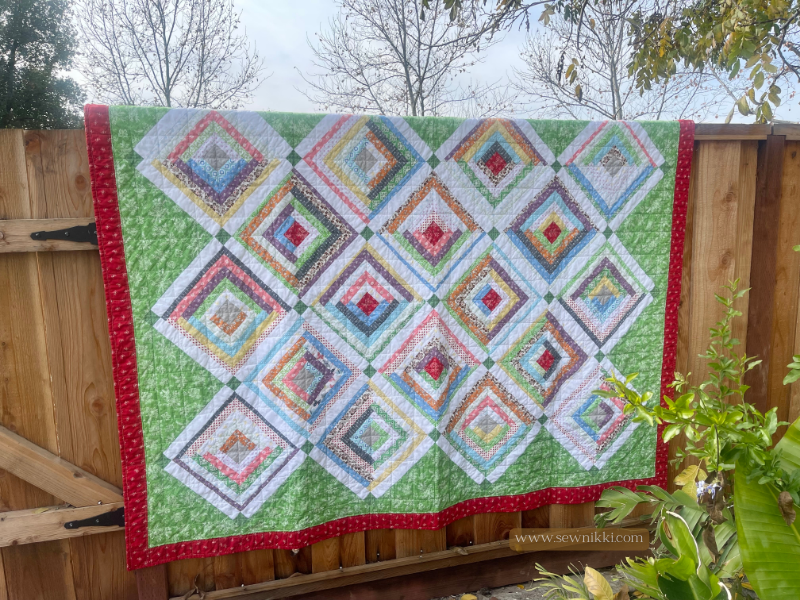 Log Cabin Quilt Pattern On Point by Sew Nikki - Completed twin size quilt hanging over fence.