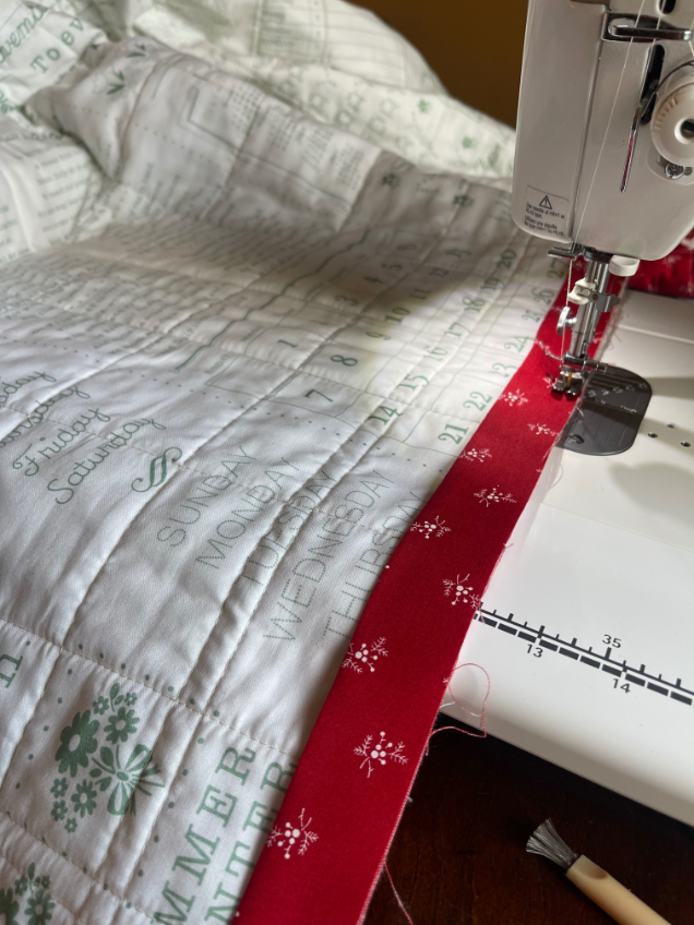 Sewing binding on quilt with machine by Sew Nikki - The folded edge of your binding strip should be lined up to the edge of your quilt.