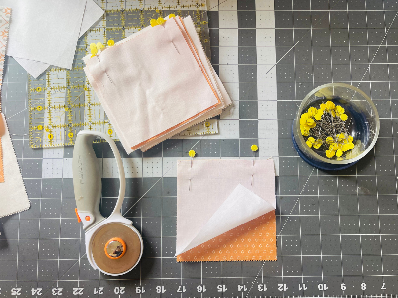 How to sew quilt square together - pinning a pair of squares in place before sewing by Sew Nikki.