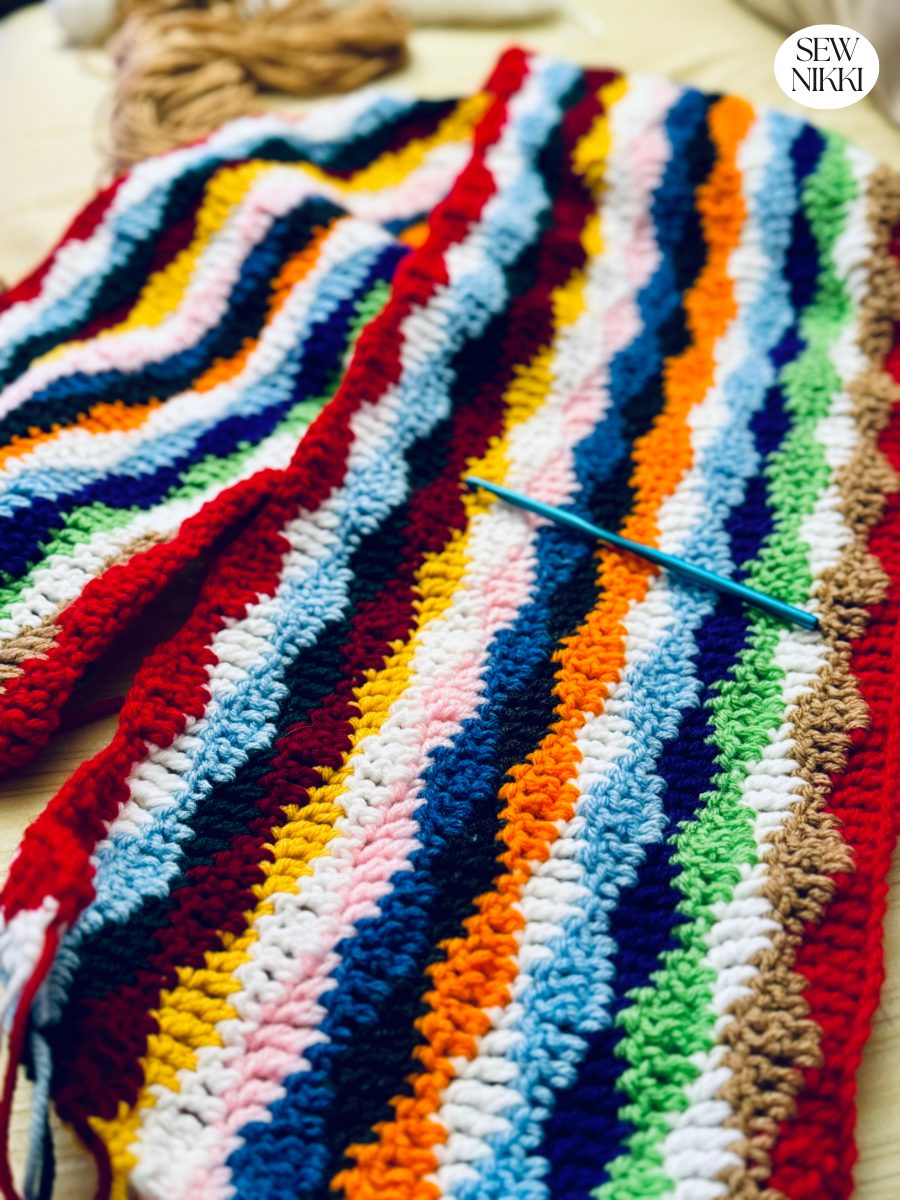 Crocheting multi colored yarn to make this vintage inspired "Wavy" free crochet scarf pattern by Sew Nikki.