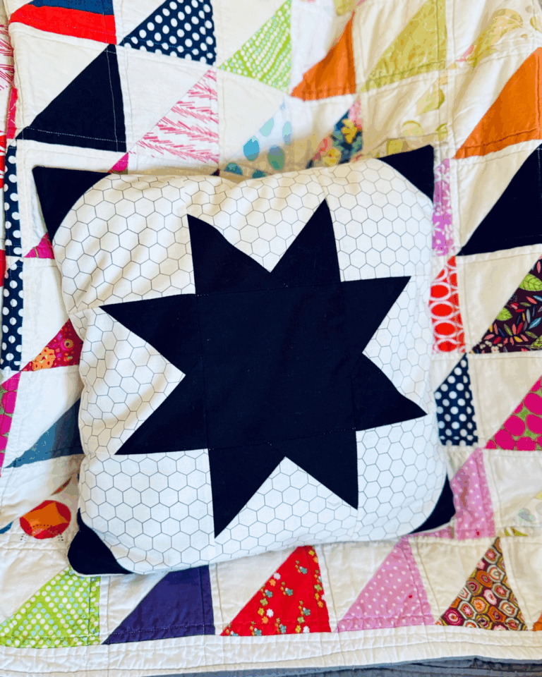 How to Sew a Zippered Pillow Cover by Sew Nikki - finished pillow on colorful quilt.