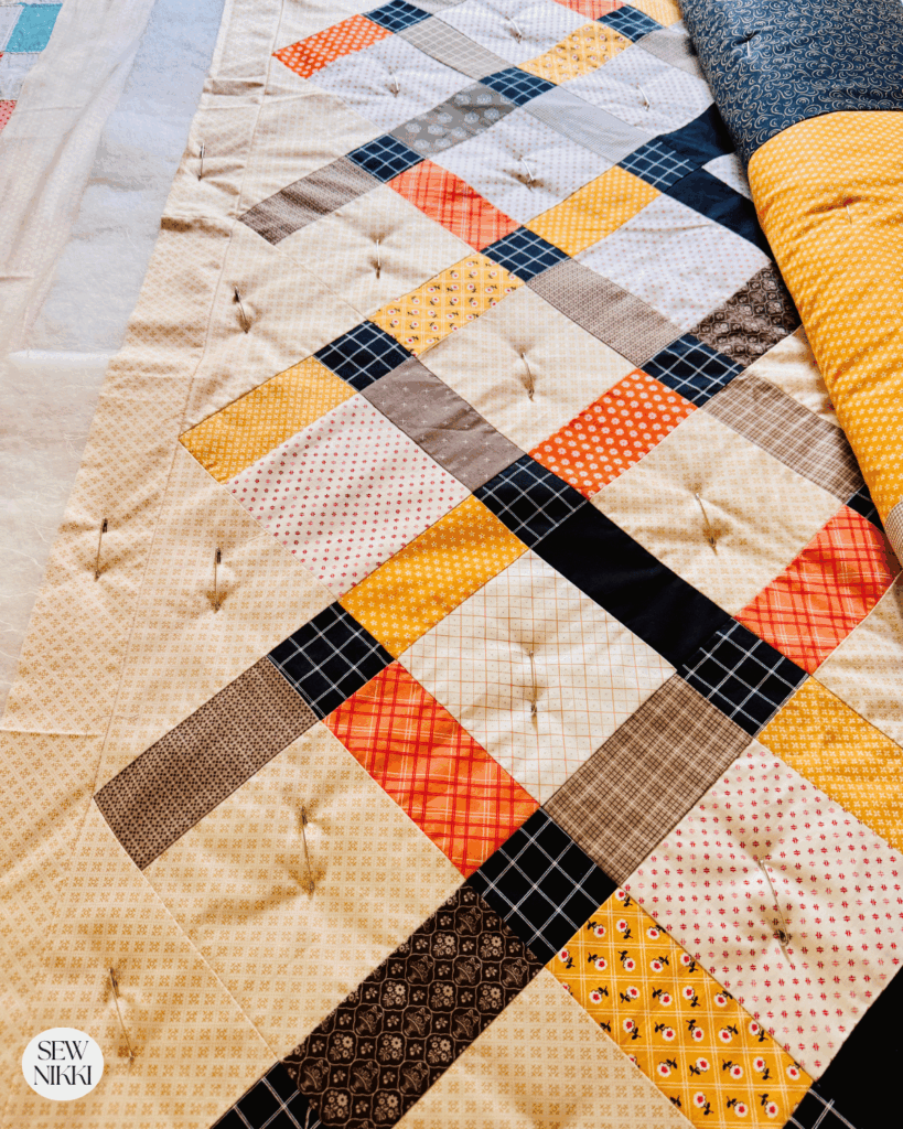 Quilt sandwich basted with safety pins on a bed