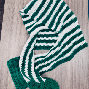 The Hoodie Scarf laying on desk, half double crochet pattern by Sew Nikki