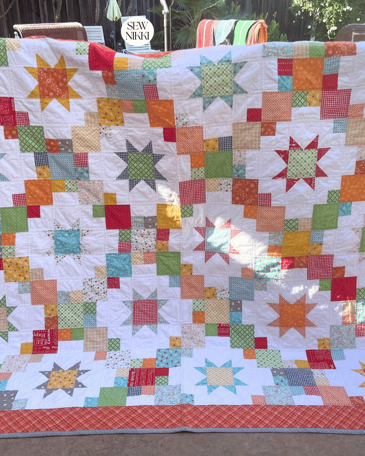 Finished Cluck Cluck Sew Brightly quilt by Sew Nikki - air drying over patio chairs outside.