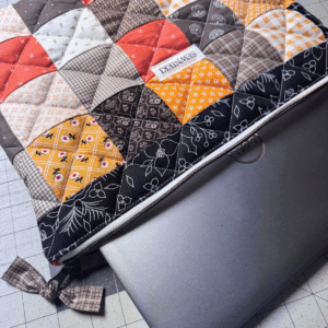 Finished quilted laptop sleeve sewing pattern by Sew Nikki with computer in it.