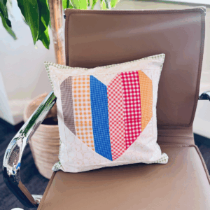Sew Nikki Free Sewing Pattern - Finished Heart Block Pillow sitting on chair.