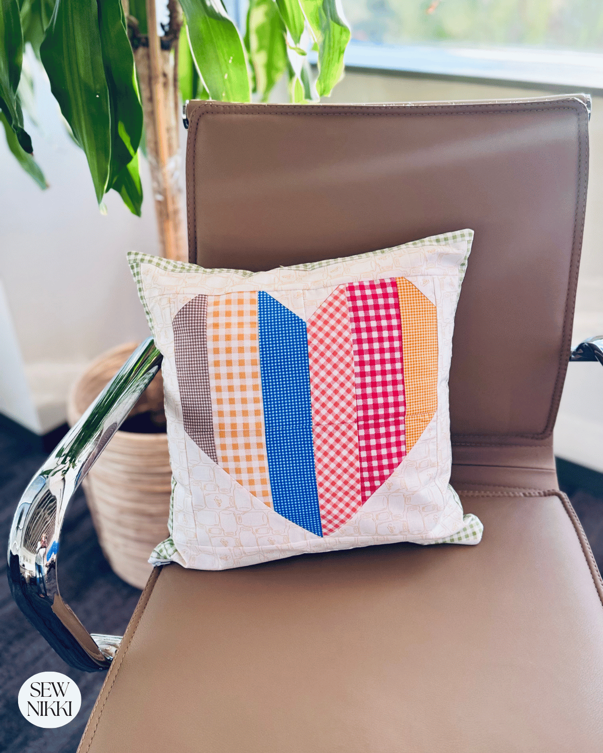 Sew Nikki Free Sewing Pattern - Finished Heart Block Pillow sitting on chair.