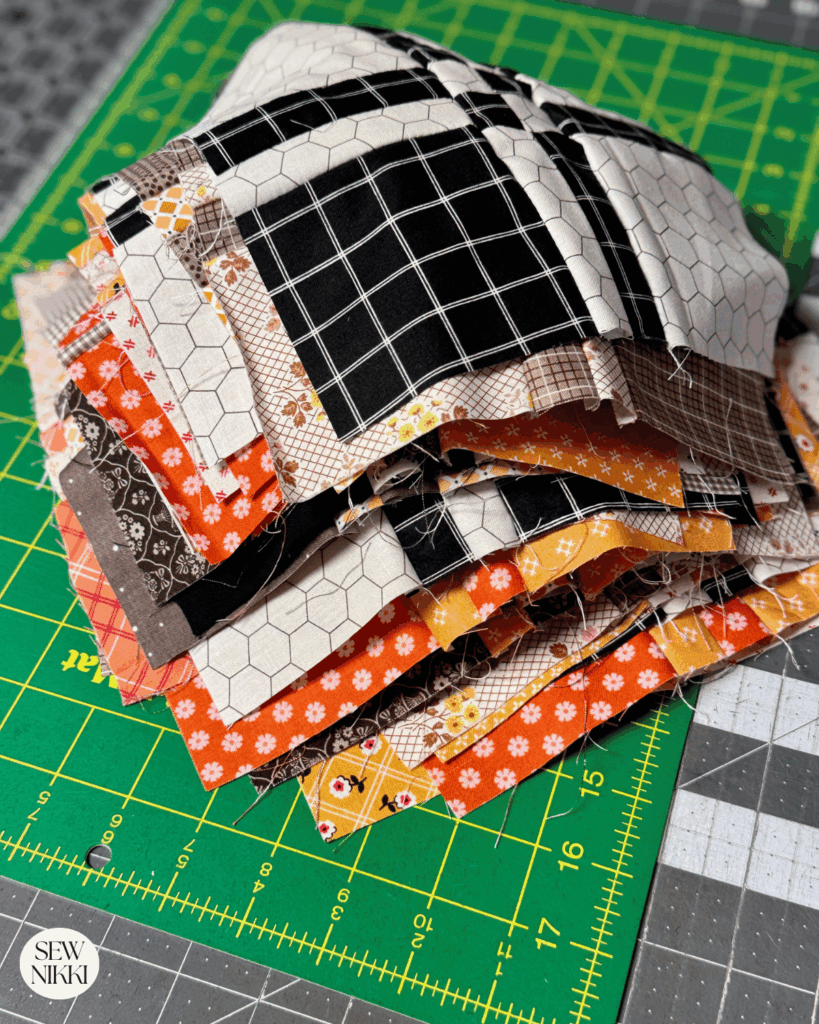 Stack of ironed disappearing four patch quilt blocks by Sew Nikki