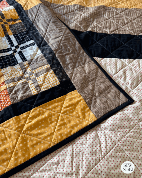 Quilt Binding Tips and Tricks for Intermediate Quilters - finished quilt with binding on home sewing machine by Sew Nikki