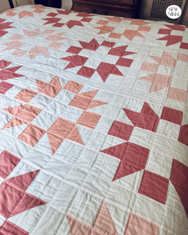 Finished Sisters Choice Quilt by Sew Nikki laying on bed.