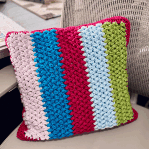 Finished crochet pillow cover with zipper by Sew Nikki sitting on a chair.