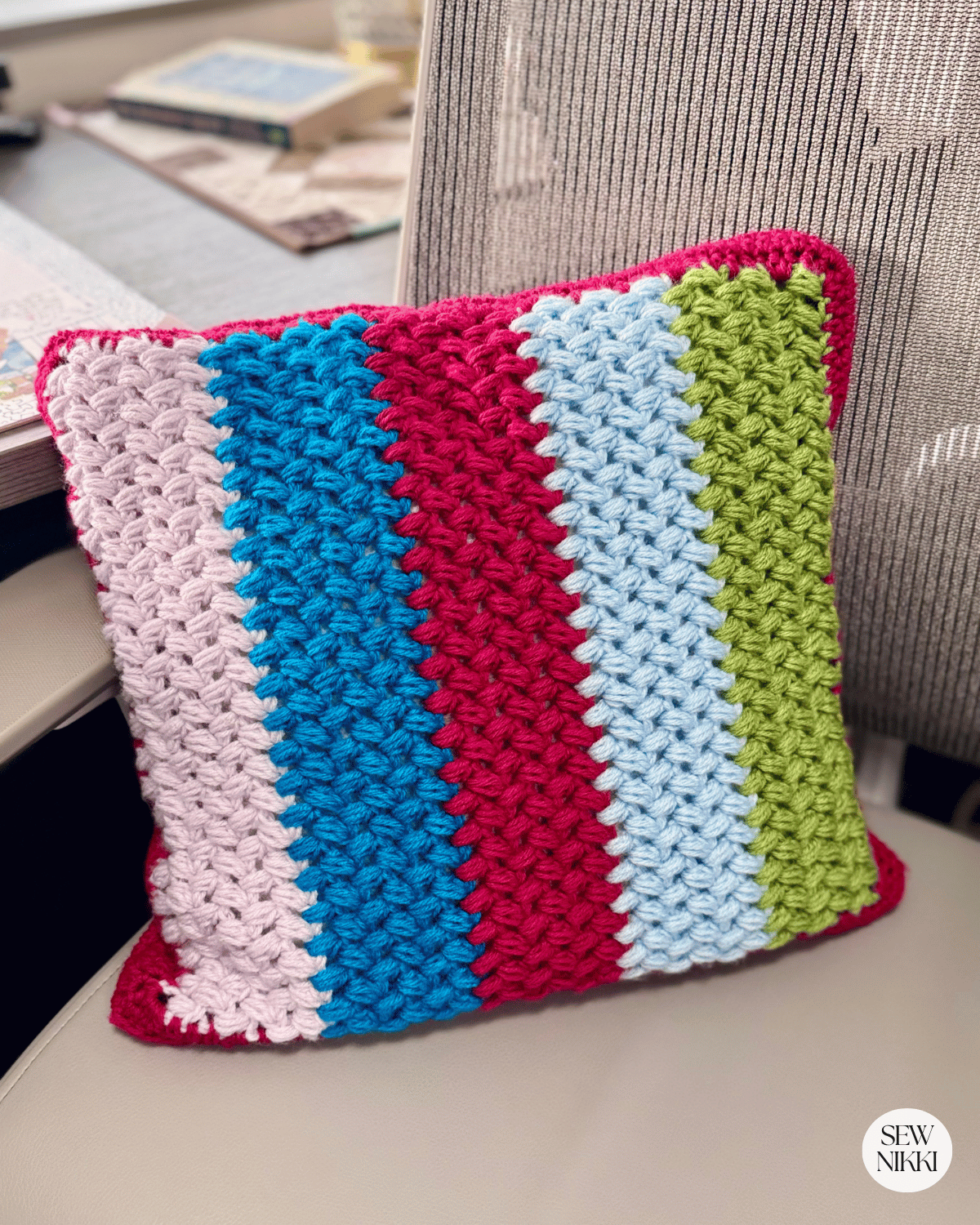 Finished crochet pillow cover with zipper by Sew Nikki sitting on a chair.