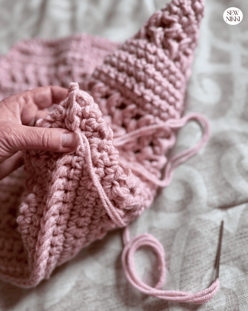 Pinch the bottom corners of the market bag and stitch a horizontal line with yarn needle from edge to edge then turn right side out by Sew Nikki