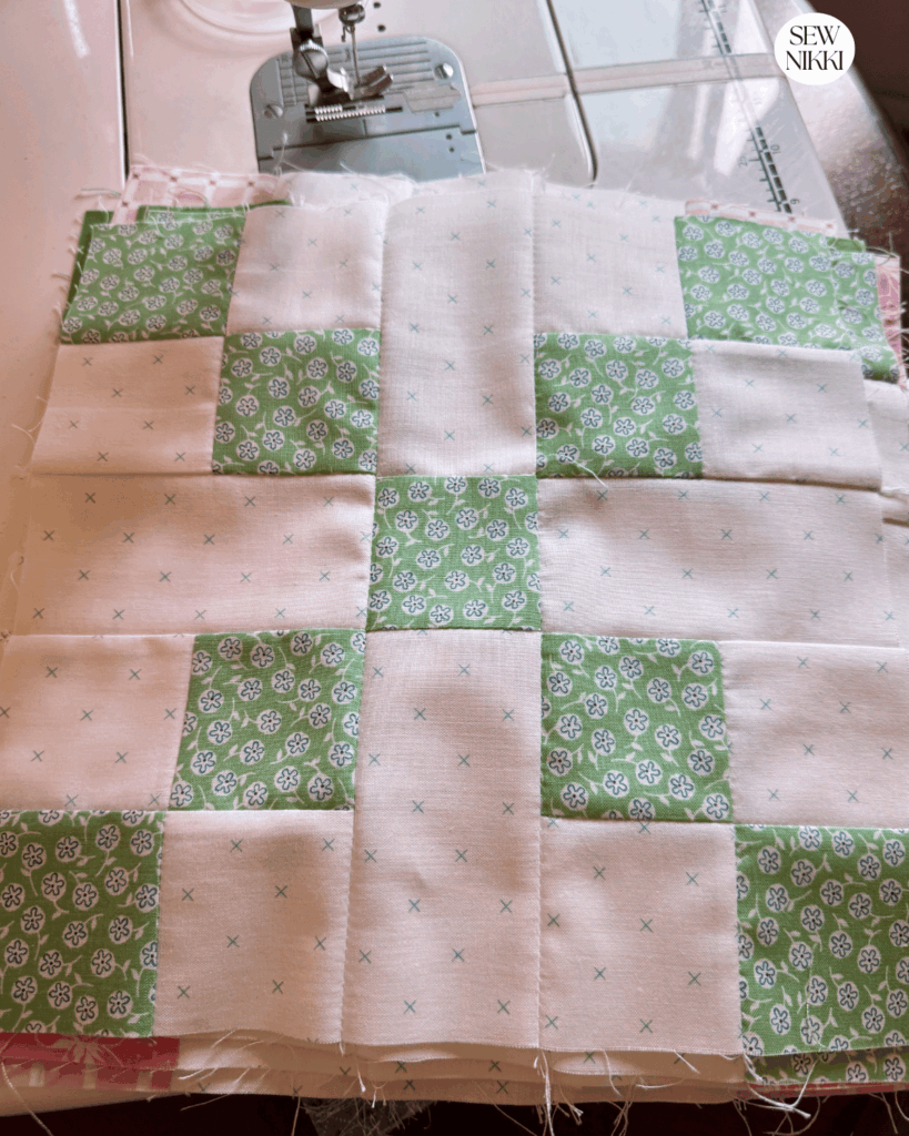 Stack of finished Irish Chain quilt blocks in scrappy fabrics by Sew Nikki