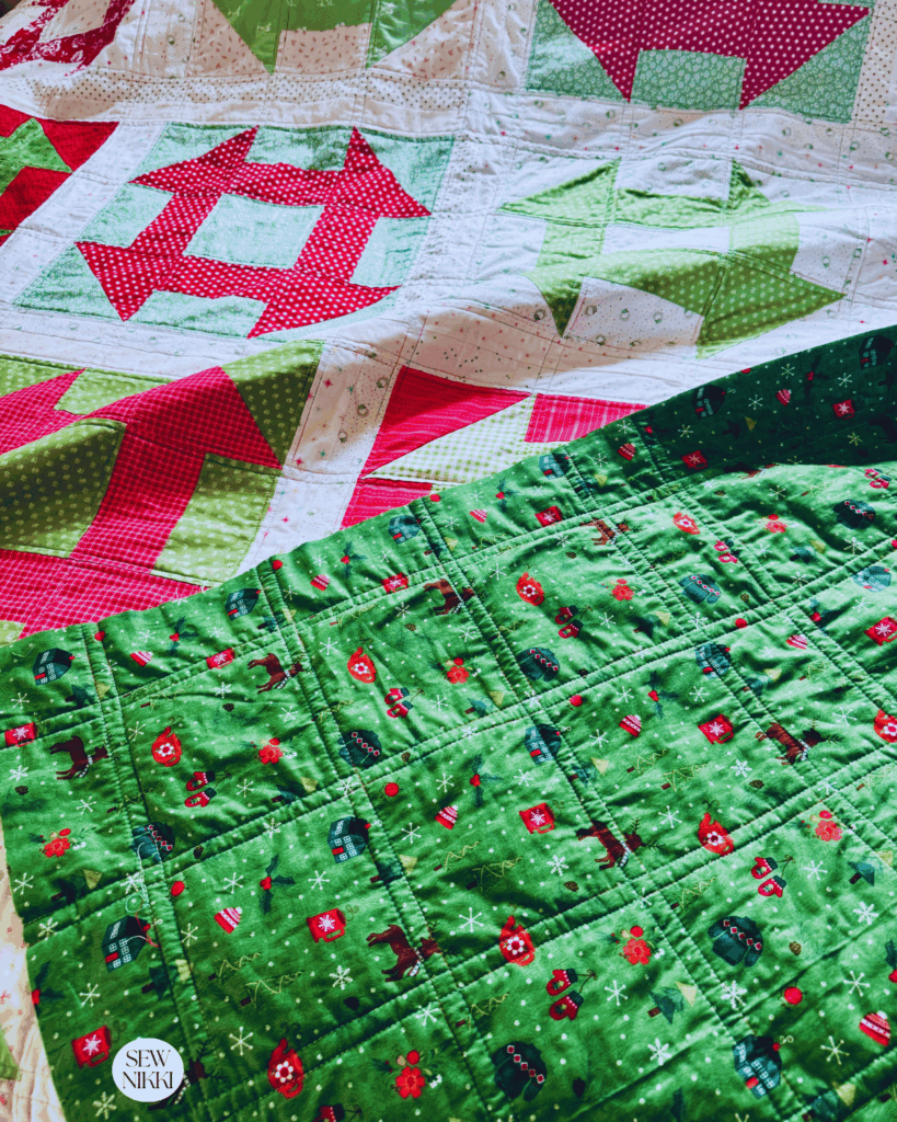 Classic Churn Dash quilt made with Christmas fabrics in a scrappy version by Sew Nikki