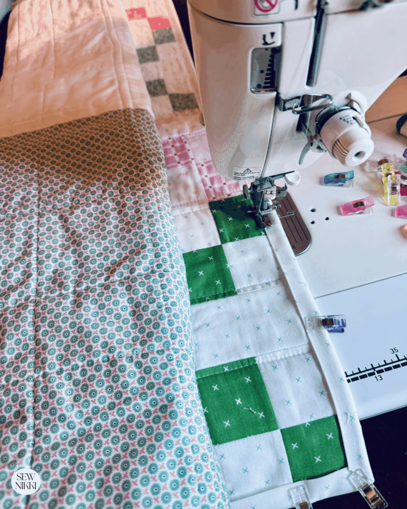 Attaching the scrappy binding to this single Irish chain variation baby quilt by Sew Nikki
