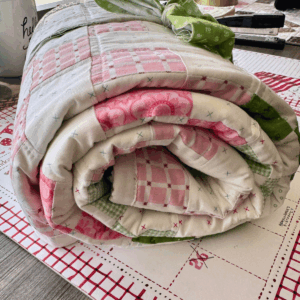 Baby quilt irish chain quilt pattern rolled up for a baby shower gift before it goes into a gift bag by Sew Nikki