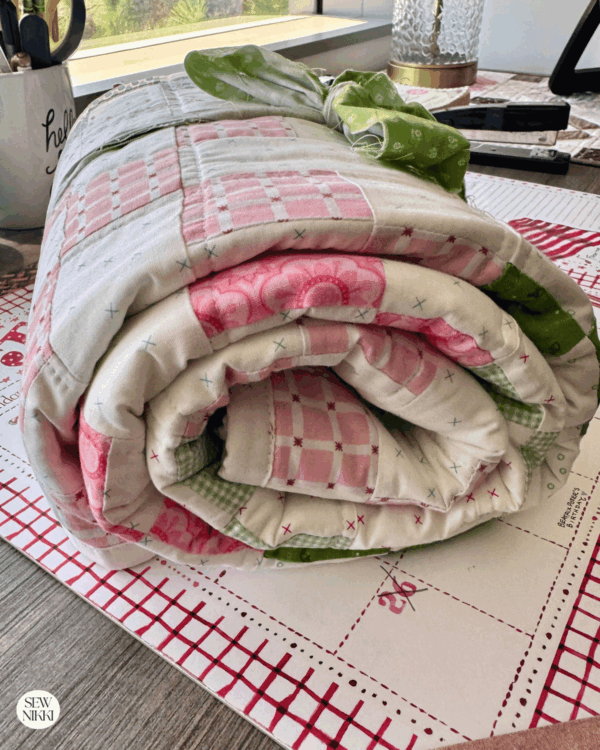 Baby quilt irish chain quilt pattern rolled up for a baby shower gift before it goes into a gift bag by Sew Nikki