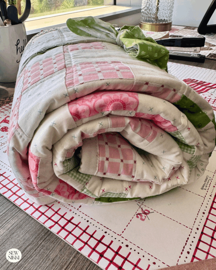Baby quilt irish chain quilt pattern rolled up for a baby shower gift before it goes into a gift bag by Sew Nikki