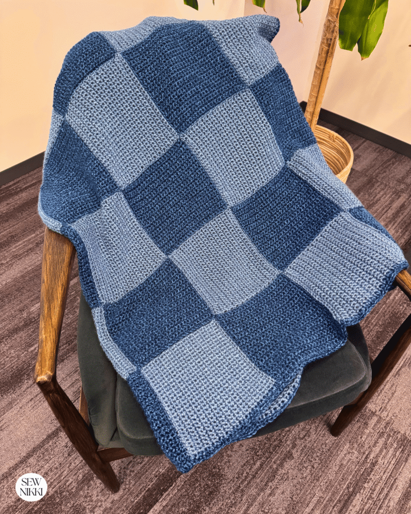 Patchwork Squares Crochet Blanket by Sew Nikki - folded blanket draped over a chair.